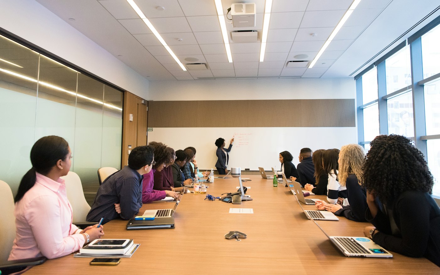 A colleague presenting at a whiteboard to her team in a meeting room